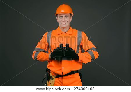 Geodesist Or Builder Foreman With A Binoculars In Hand Isolated On Gray Background.