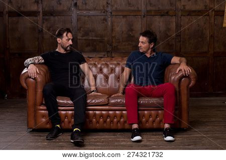 Calm Thoughtful Middle Aged Man Sitting On The Sofa And Carefully Touching The Surface Of It While T