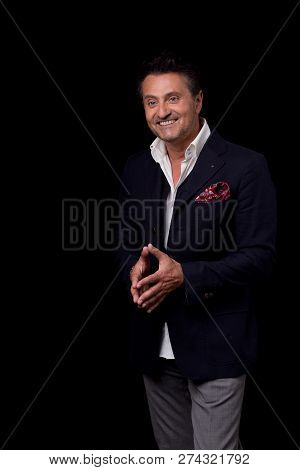 Happy Elegant Man In Dark Suit Putting His Fingers Together And Smiling While Standing Against The B