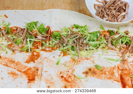 Shawarma, Vegetables And Seasoning On A Flatbread During Preparing And Wrapping In To Flatbread