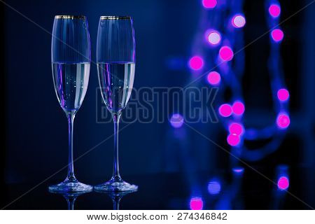 Holiday Pair Of Glasses Of Champagne In The Interior. Blurred Luminocity Neon Color Backdround. Chri