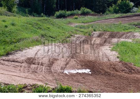 Dirty Road Over The Hills For Motocross, Along The Edges Of The Road Growing Grass And Trees