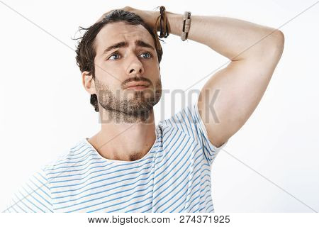 Unretouched Shot Of Dramatic Upset Good-looking Guy With Beard And Mascules Combing Hair Behind With