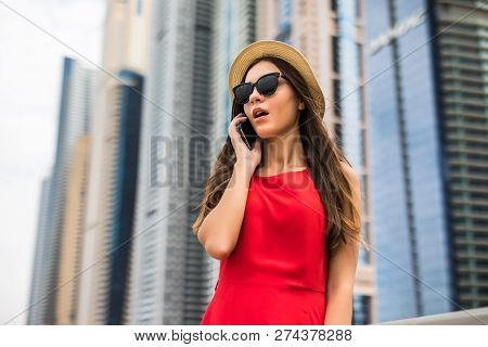 Portrait Of Young Woman In Red Dress, Sunglasses And Summer Hat Talking On The Phone Get Shocked New
