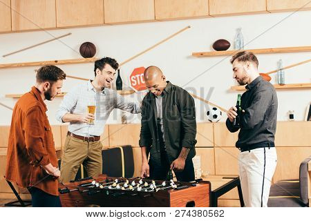 Multiracial Young Friends Playing Table Football Together In Cafe