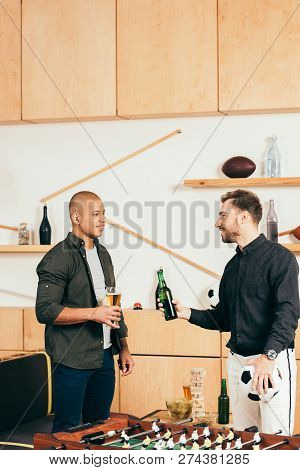 Side View Of Multicultural Men With Beer Having Conversation In Cafe