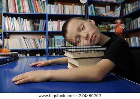 Boy Tired Sleeping On Pile Of Book In Library