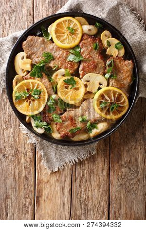 Tasty Italian Fillet Of Veal Scaloppini With Mushrooms And Lemons In Sauce Close-up In A Frying Pan.