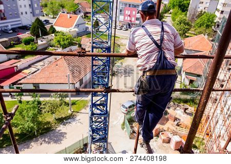 Rigger Is Standing High Up On Scaffold, Risk At Construction Site.