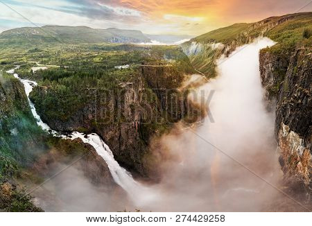 Beautiful View Of Waterfall. Summer Landscape In The Mountains With A Waterfall And Fog. Foggy Weath