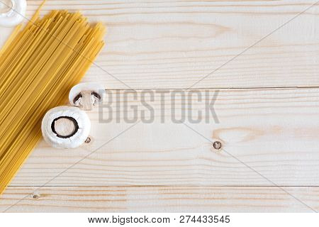 Wooden Background With Spaghetti And Mushrooms. Food Background Italian. Raw Champignons And Pasta O