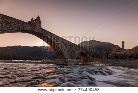 Landscape Of A Medieval Bridge Over A Turbulent River At Sunset