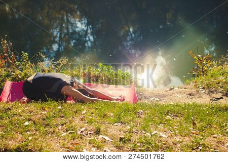 Stretching Out Woman On Pink Yogamat By The River