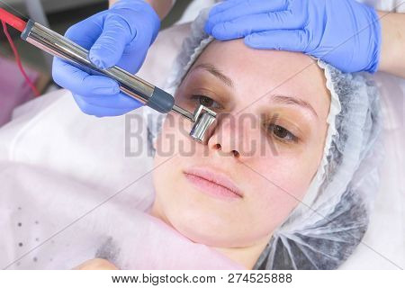 Cosmetologist Makes A Micro-current Procedure For The Face Of A Young Woman. Face Close-up, Front Vi