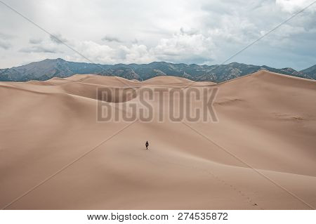 A Man Walking The Giant Sand Dunes At Great Sand Dunes National Park In Colorado, Usa