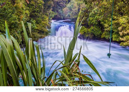 Powerful stormy waterfall Huka in the narrow riverbed.  New Zealand, North Island. The concept of active and phototourism