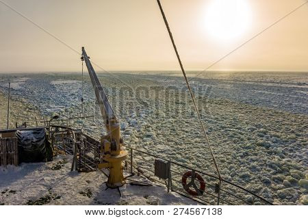 Dim polar sun in Lapland. The strip of ice crumb spreads behind the icebreaker. The excursion to the arctic tourist cruise on the sea icebound. The concept of active and extreme tourism