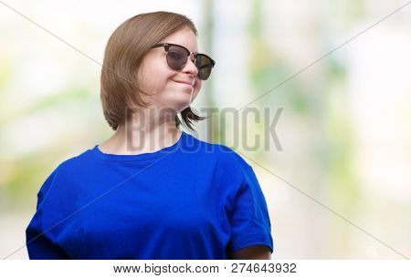 Young adult woman with down syndrome wearing sunglasses over isolated background looking away to side with smile on face, natural expression. Laughing confident.