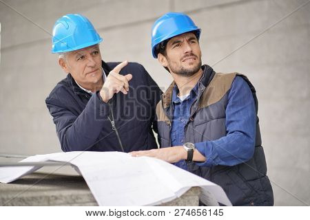 Workman pointing and showing something to employee on modern building sight