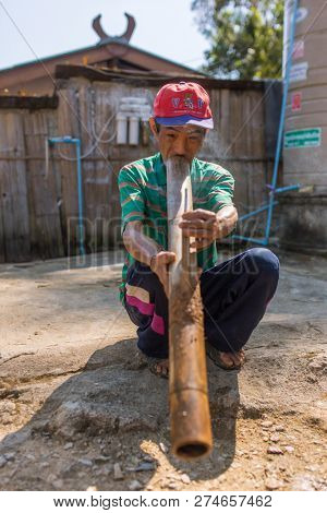 Chiang Rai, Thailand - February 8, 2017: Unidentified elderly Akha man is smoking traditional tobacco pipe in Akha hilltribe village in Northern Thailand