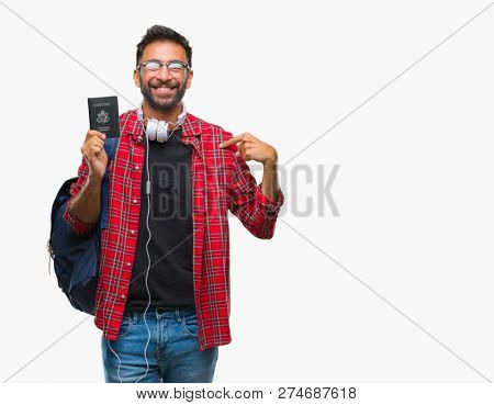 Adult hispanic student man holding passport of america over isolated background with surprise face pointing finger to himself