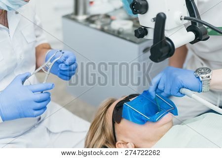 Doctor Used Microscope. Dentist Is Treating Patient In Modern Dental Office. Operation Is Carried Ou