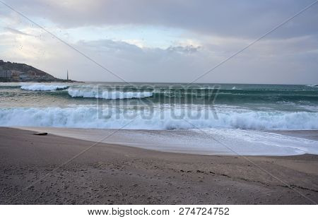 Waves Breaking Against Riazor Beach With Sunset Light. Wild Sea With Foam. La Coruna, Spain, Autumn 