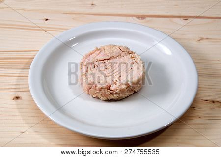 Solid White Albacore Tuna Fish Up Close On White Plate Still Shaped Like The Can It Came In On Woode