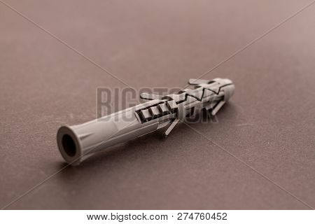 Gray Plastic Wall Plug And Building Anchor Lies On A Smooth Gray Surface. Universal Plastic Mounting