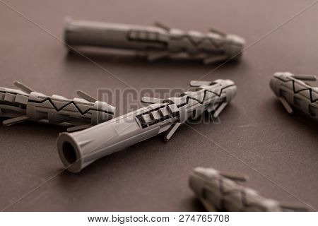 Gray Plastic Wall Plugs And Building Anchors Are Lying On A Smooth Gray Surface. Universal Plastic M