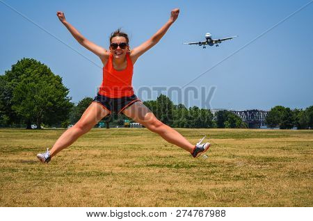 Adult Woman At Gravelly Point Park In Washington Dc Jumps As An Airplane Flies In For A Landing At T