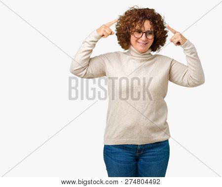 Beautiful middle ager senior woman wearing turtleneck sweater and glasses over isolated background Smiling pointing to head with both hands finger, great idea or thought, good memory