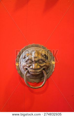 Red Wooden Door Of The Temple With The Brass Door Knocker