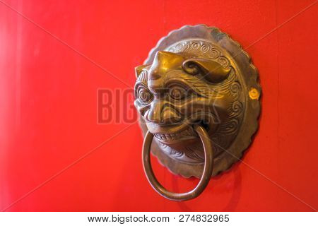 Red Wooden Door Of The Temple With The Brass Door Knocker