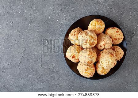 Overhead View Of Gougeres, Cheese Puffs Balls On A Black Plate. Traditional French Cheese Choux Buns