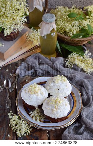 Chocolate Capcakes With Vanilla Cream Sprinkled With White Chocolate And Elderberry Flowers. Vintage