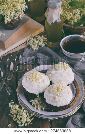 Chocolate Capcakes With Vanilla Cream Sprinkled With White Chocolate And Elderberry Flowers. Vintage