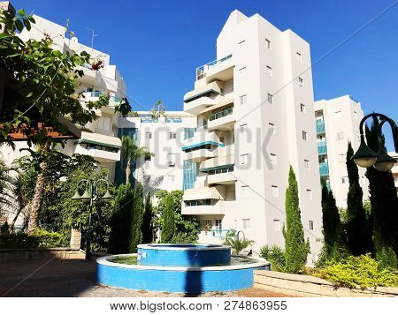 Residential Buildings And Fountain Surrounded With Green Plants In  Rishon Le Zion.