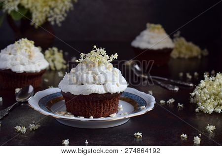 Chocolate Capcakes With Vanilla Cream Sprinkled With White Chocolate And Elderberry Flowers. Vintage