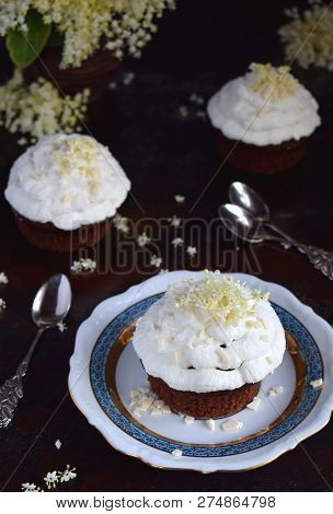 Chocolate Capcakes With Vanilla Cream Sprinkled With White Chocolate And Elderberry Flowers. Vintage