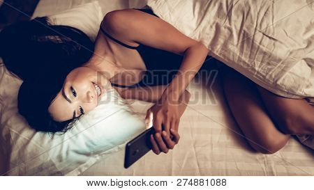 Girl Texting On Mobile Phone In Low Light. Girl Using Smartphone On Bed Before Sleeping. Mobile Addi