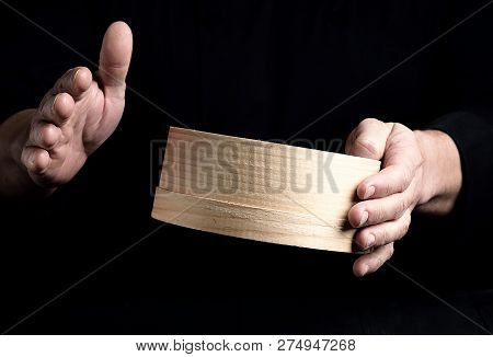 Two Male Chef Hands Hold A Round Wooden Sieve For Flour, Black Background