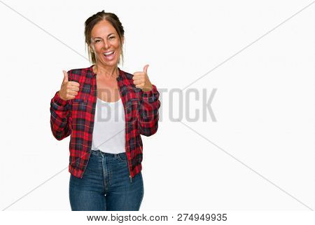 Middle age adult woman wearing casual jacket over isolated background success sign doing positive gesture with hand, thumbs up smiling and happy. Looking at the camera with cheerful expression, winner