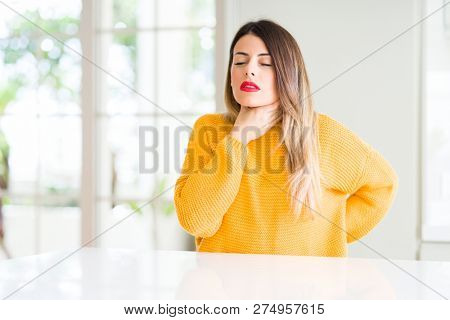 Young beautiful woman wearing winter sweater at home Touching painful neck, sore throat for flu, clod and infection