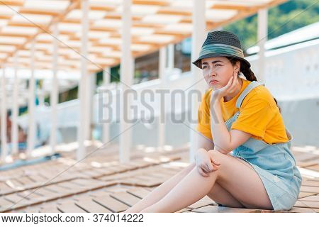 Emotion Of Sadness And Discontent. Portrait Of Young Woman In A Straw Hat Leaned On Her Hand In Disc