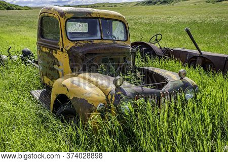 Abandoned Antique Yellow Truck And Tractor In The Tall Grass On A Hillside Near Wymark, Sk