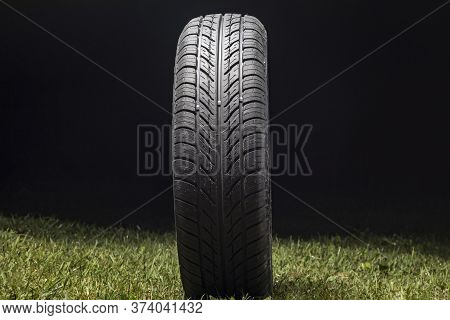 Car Tire In Dark Color. Night Shooting. The Tread Is Summer. Light Falls From Above.