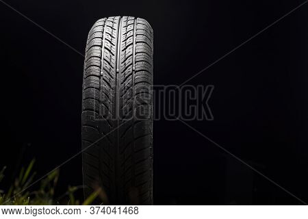 Car Tire In Dark Color. Night Shooting. The Tread Is Summer. Light Falls From Above