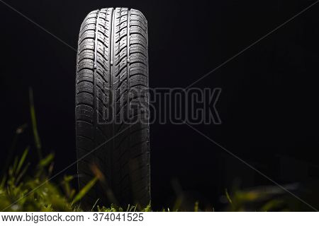 Car Tire In Dark Color. Night Shooting. The Tread Is Summer. Light Falls From Above.