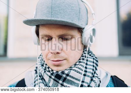 A Caucasian Man In A Gray Cap Is Saddened Listening To Music.
